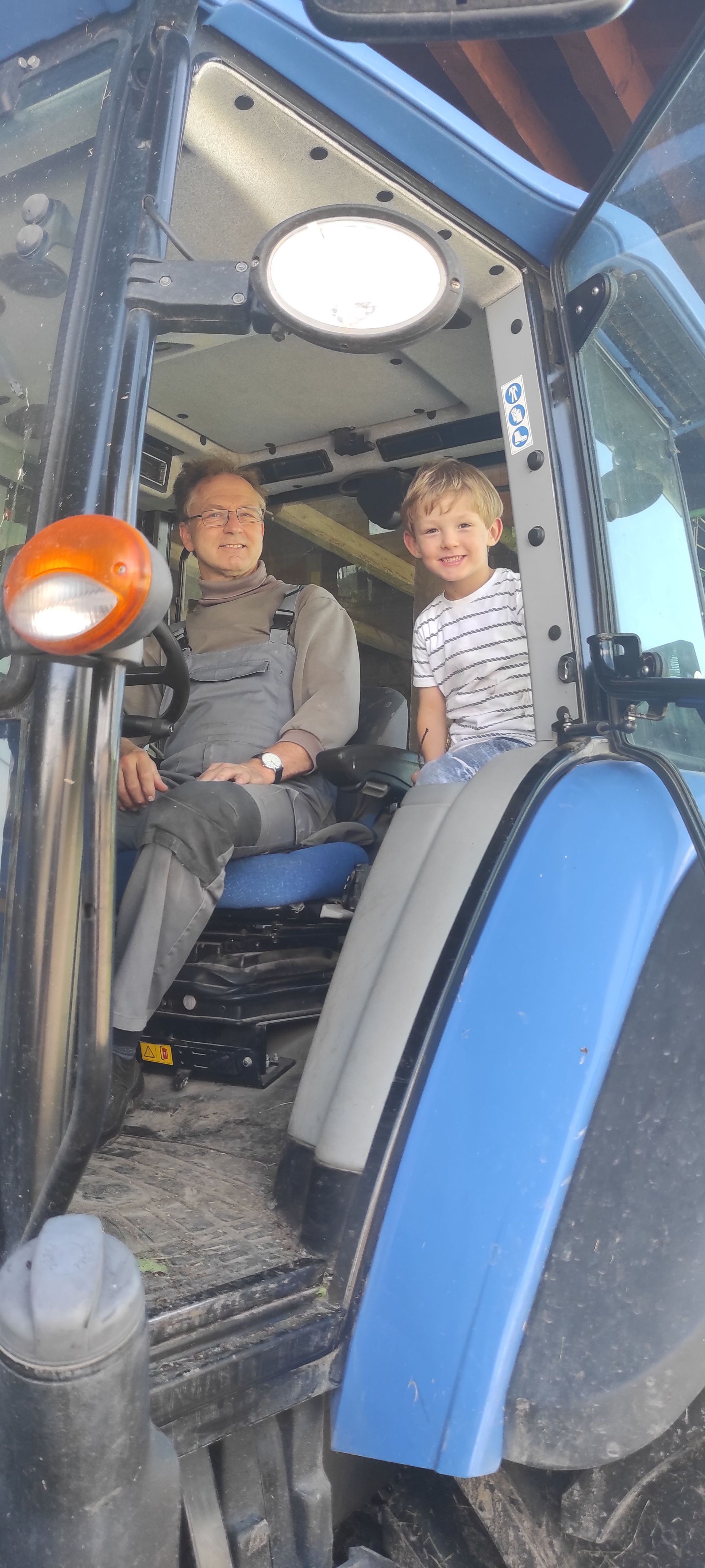 Kinder fahren auf dem großen Traktor auf dem Sonnenhof mit